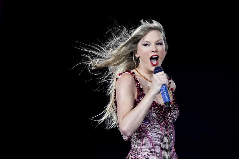Taylor Swift sings with a mic to her mouth, wearing a sequined leotard amid a dark backdrop