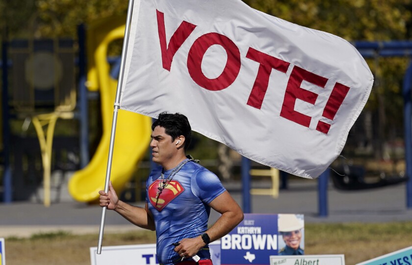 A jogger in San Antonio carries a "Vote!" flag as he passes a polling station on Nov. 3, 2020.