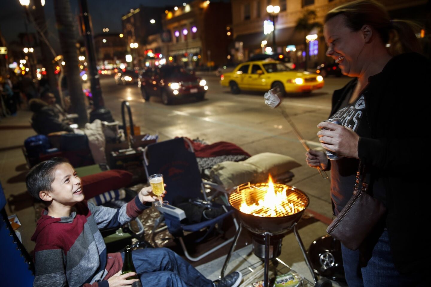 Jarod Gutierrez, 12, of Corona, prepares some sparkling cider while his mother, Susan, roasts marshmallows on Colorado Boulevard while camping out overnight.