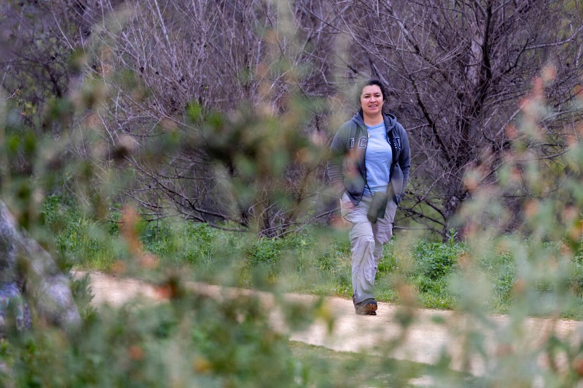 A woman walks along a path, shrouded by vegetation