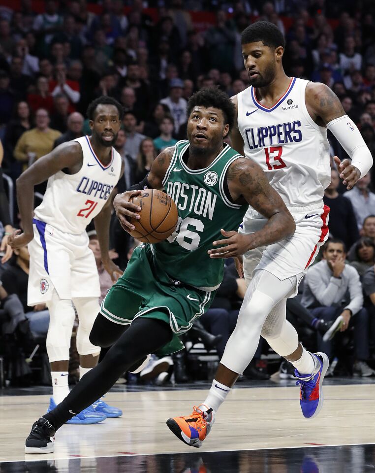 Celtics guard Marcus Smart splits the defense of Clippers Patrick Beverley, left, and Paul George en route to a basket during the fourth quarter of a game Nov. 20 at Staples Center.