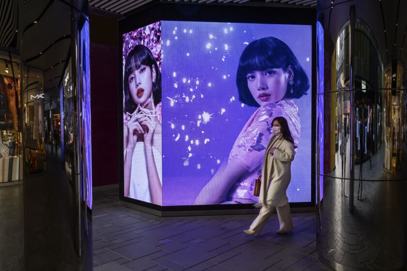 BEIJING, CHINA - DECEMBER 09: A woman walks by an ad for a cosmetic company as part of a display at a shopping mall on December 9, 2020 in Beijing, China. The revival of consumer consumption is expected to continue to boost China's economy, which is already showing strong signs of post-pandemic recovery and providing a bright spot for global brands and retailers. (Photo by Kevin Frayer/Getty Images)