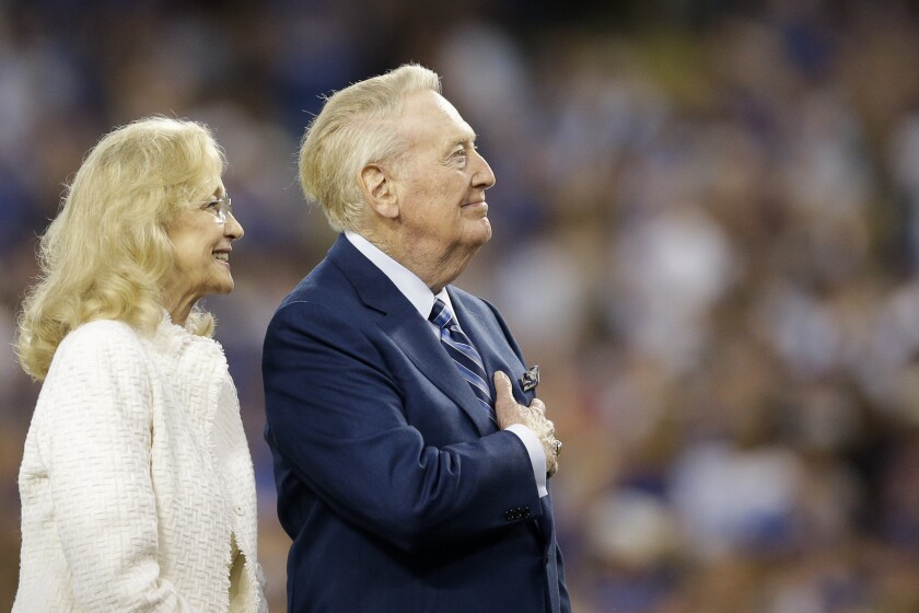 Vin Scully holds his hand over his heart as he stands next to his wife, Sandi.
