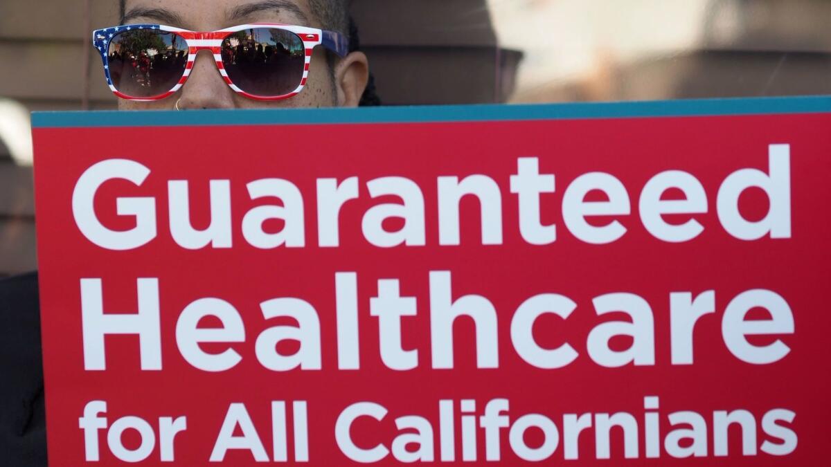 A participant in a rally in support of single-payer healthcare in California holds a sign outside Assembly Speaker Anthony Rendon's office in South Gate in June 2017.