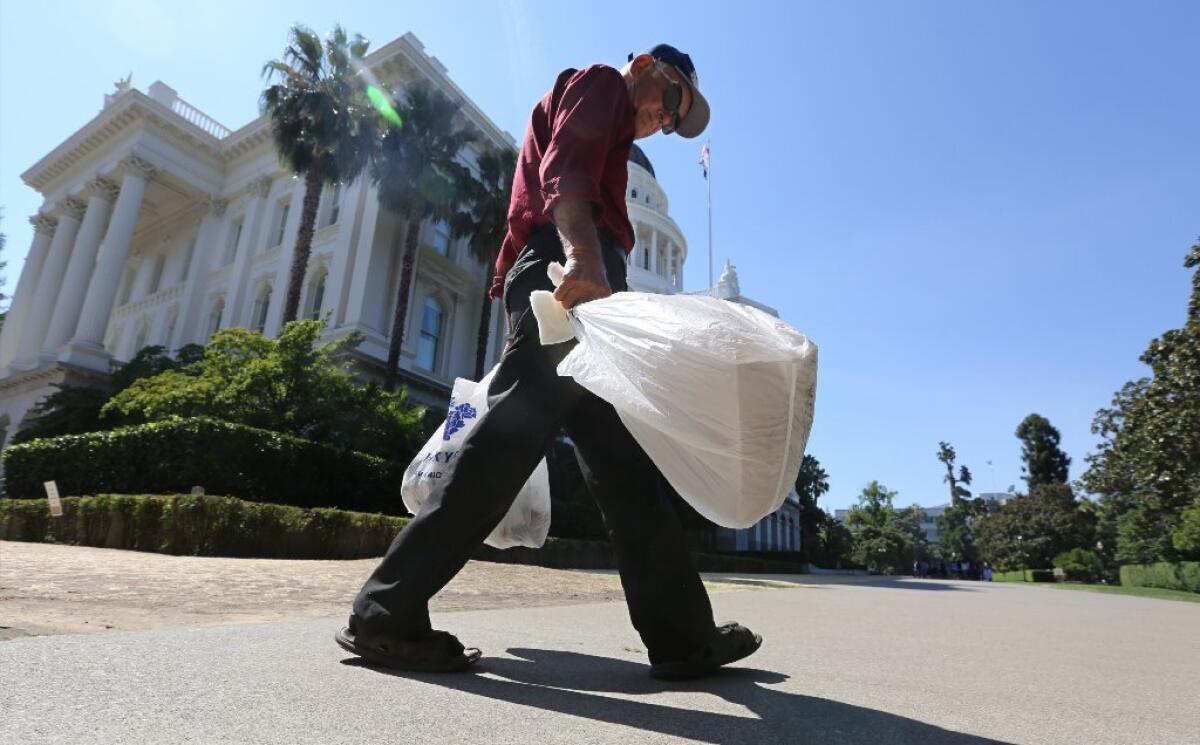 A man carries plastic single-use bags past the state Capitol in Sacramento last August.