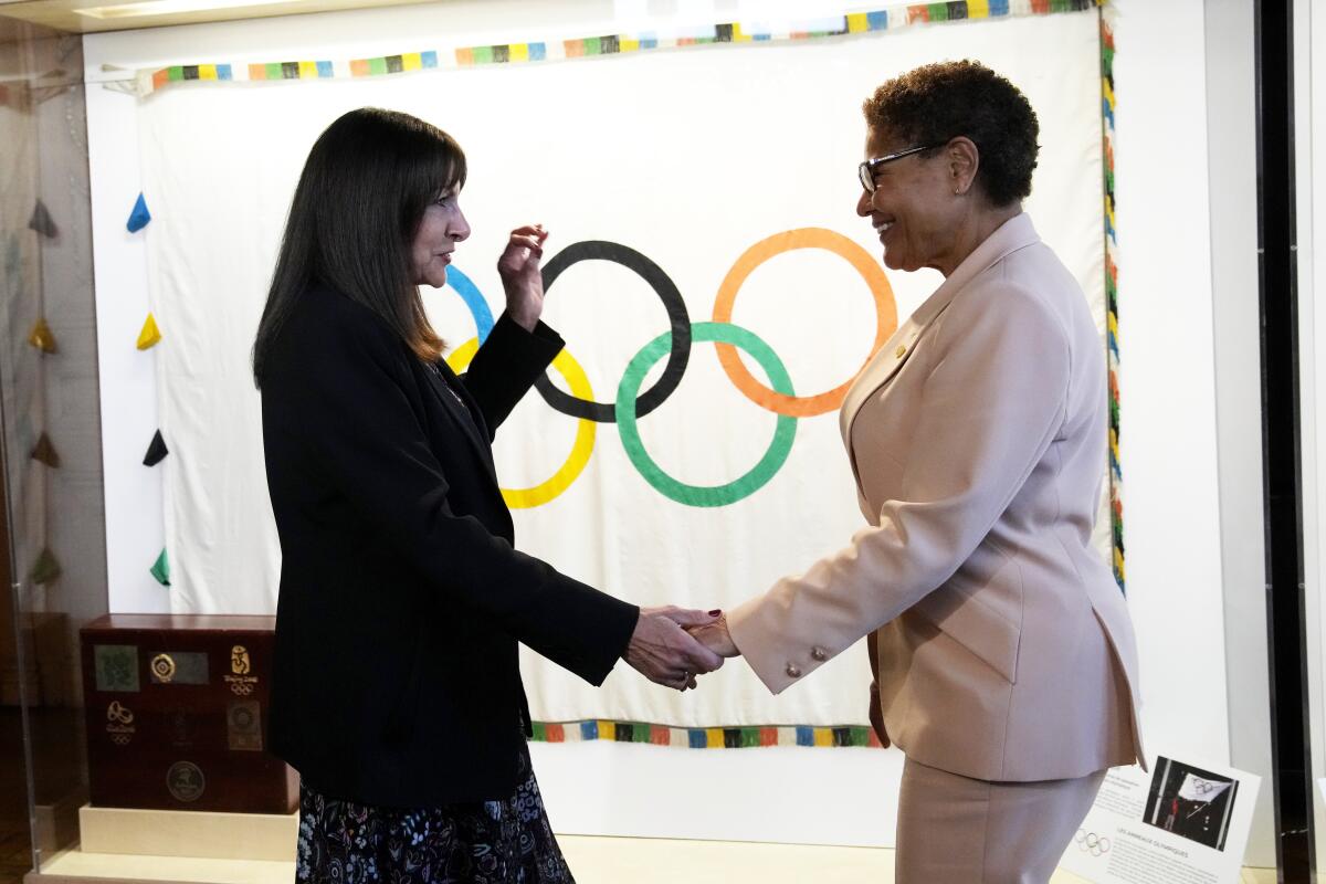Paris Mayor Anne Hidalgo, left, speaks with Los Angeles Mayor Karen Bass in front of a banner with Olympic rings