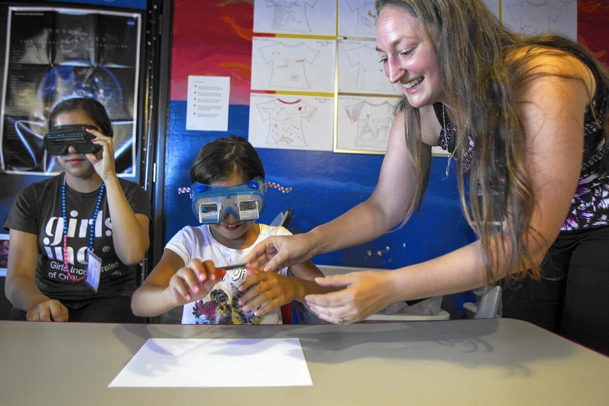Laura Smith-Velazquez, a candidate for the Mars One mission, works with Haley Rodriguez, 8, and Gabriela Jimenez, 16, as they attempt to draw a smiley face while wearing prism glasses at Girls Inc. on Friday.