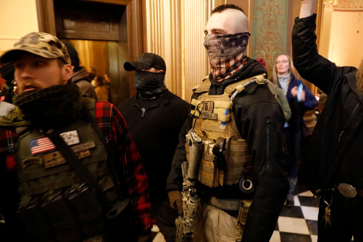 A protester bearing a weapon and dressed in a bulletproof vest tries to enter the Michigan State Capitol