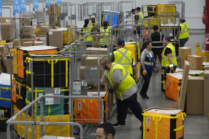 ARCHIVO - Empleados de Amazon colocan paquetes en carritos antes de cargarlos en camiones para su distribución a los clientes durante el evento anual Prime Day de Amazon, en la estación de reparto DAX7 de la empresa, el 16 de julio de 2024, en South Gate, California. (AP Foto/Richard Vogel, Archivo)