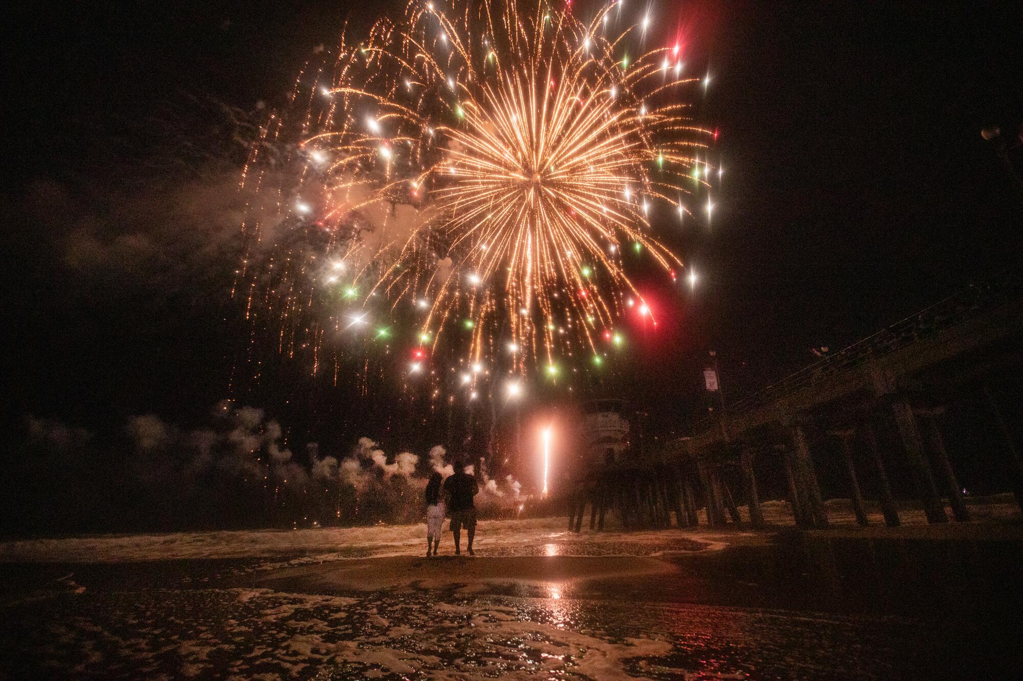 A couple wades into the ocean during the fireworks show.