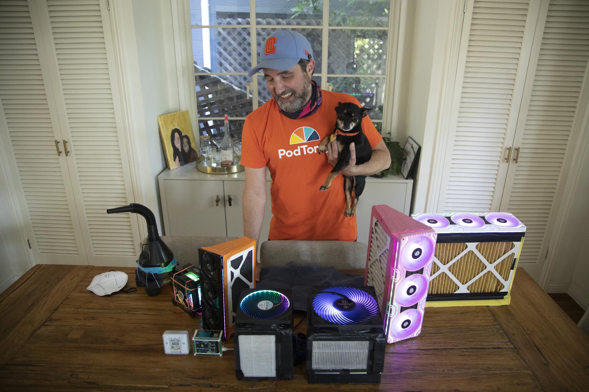 Alex LeVine holds his dog in one hand and shows off an array of air filter systems.