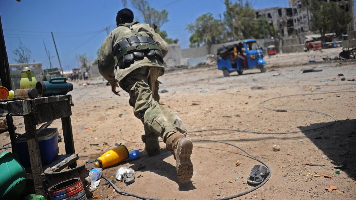 A Somali soldier runs for cover at the scene of two explosions near the ministries of public works and labor in Mogadishu.