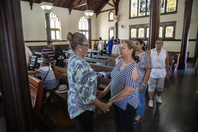 LINCOLN HEIGHTS, CALIF. -- SUNDAY, AUGUST 11, 2019: Parishioners greet each other after the homily during Sunday service at Church of the Epiphany in Lincoln Heights, Calif., on Aug. 11, 2019. (Brian van der Brug / Los Angeles Times)