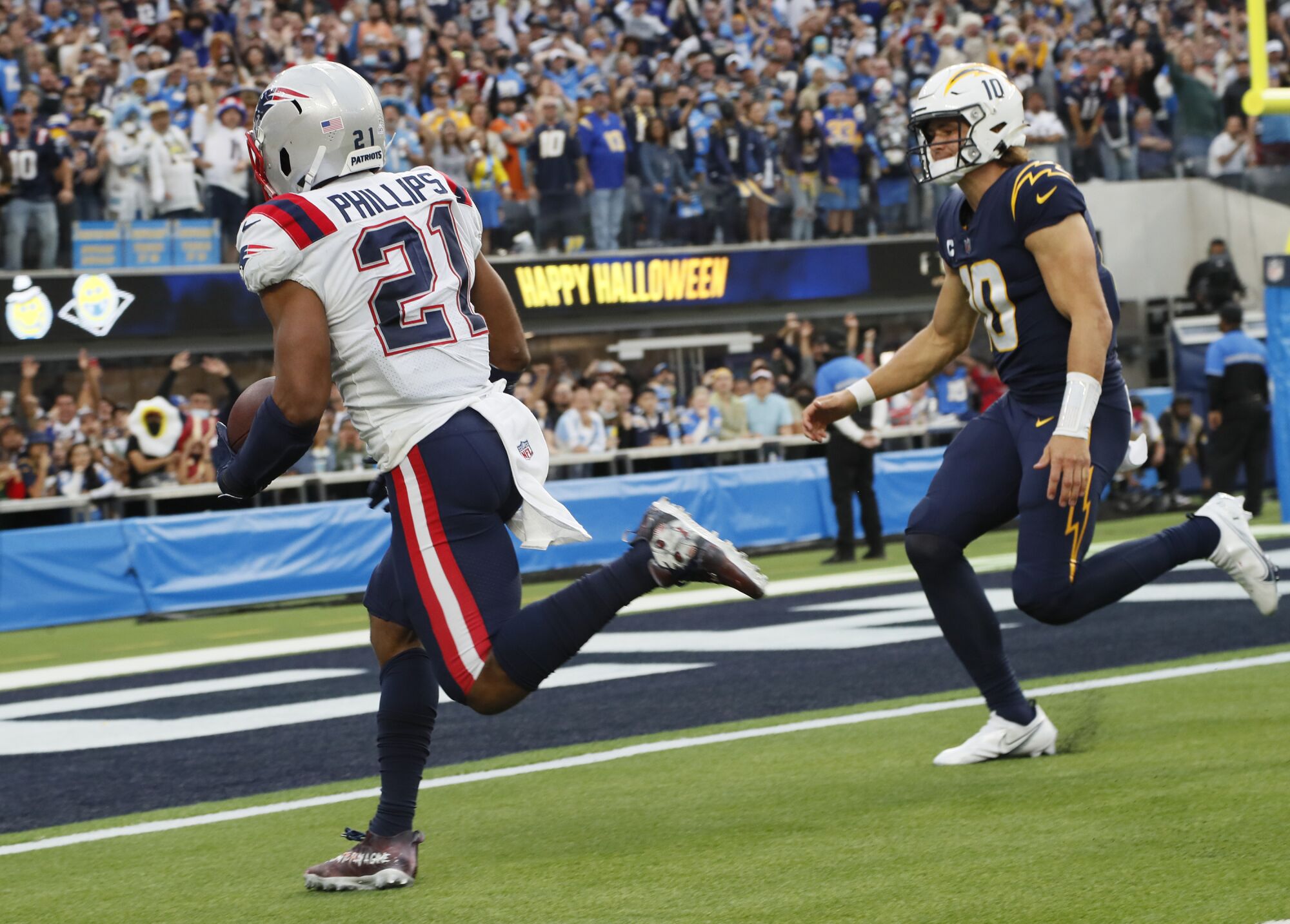 New England Patriots safety Adrian Phillips scores on an interception return past Chargers quarterback Justin Herbert.