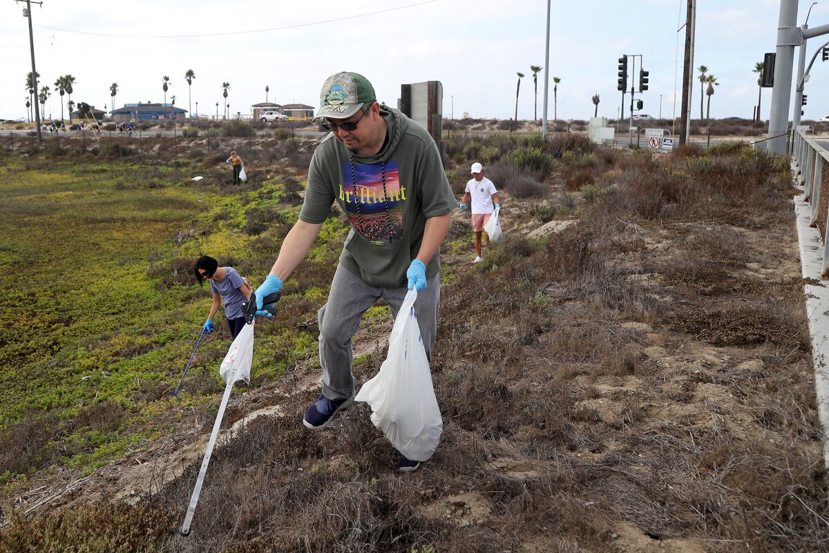 David Lo and other volunteers help remove trash at Talbert Marsh during a coastal cleanup event in Huntington Beach.