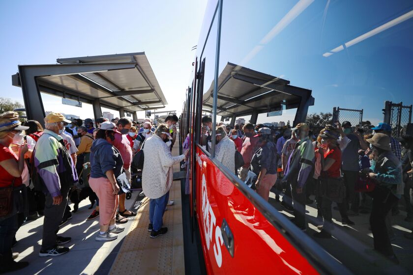 SAN DIEGO, CA - NOVEMBER 21: People board the Mid-Coast Extension of the UC San Diego Blue Line Trolley during a grand opening celebration on Sunday, Nov. 21, 2021 in San Diego, CA. (K.C. Alfred / The San Diego Union-Tribune)