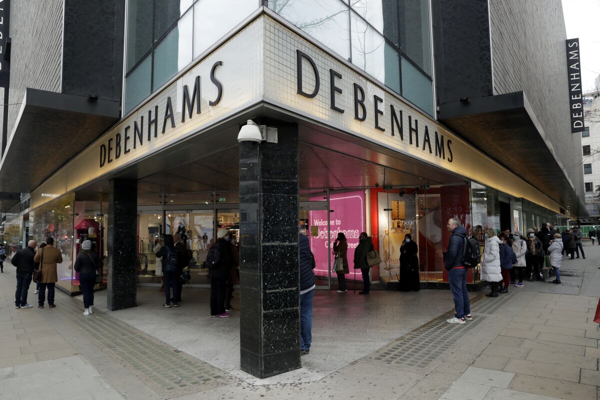 People queue up waiting for the Debenhams department store, which is expected to close down, to open for the day's trading as non-essential shops are allowed to reopen after England's second lockdown ended at midnight, on Oxford Street, in London, Wednesday, Dec. 2, 2020. In another dark day for the British retailing industry, Debenhams said Tuesday it will start liquidating its business after a potential buyer of the company pulled out, a move that looks like it will cost 12,000 workers their jobs. (AP Photo/Matt Dunham)