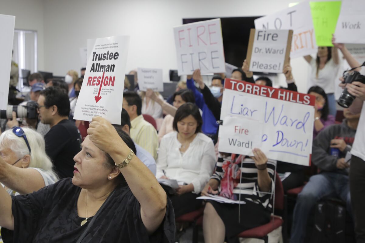 Community members hold up competing signs at San Dieguito Union High School District's latest school board meeting on May 19.