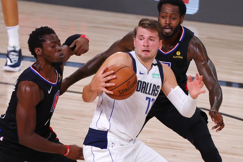 Dallas Mavericks' Luka Doncic (77) is pressured by Los Angeles Clippers' Reggie Jackson (1) and JaMychal Green, right, during the third quarter of Game 1 of an NBA basketball first-round playoff series, Monday, Aug. 17, 2020, in Lake Buena Vista, Fla. (Kevin C. Cox/Pool Photo via AP)