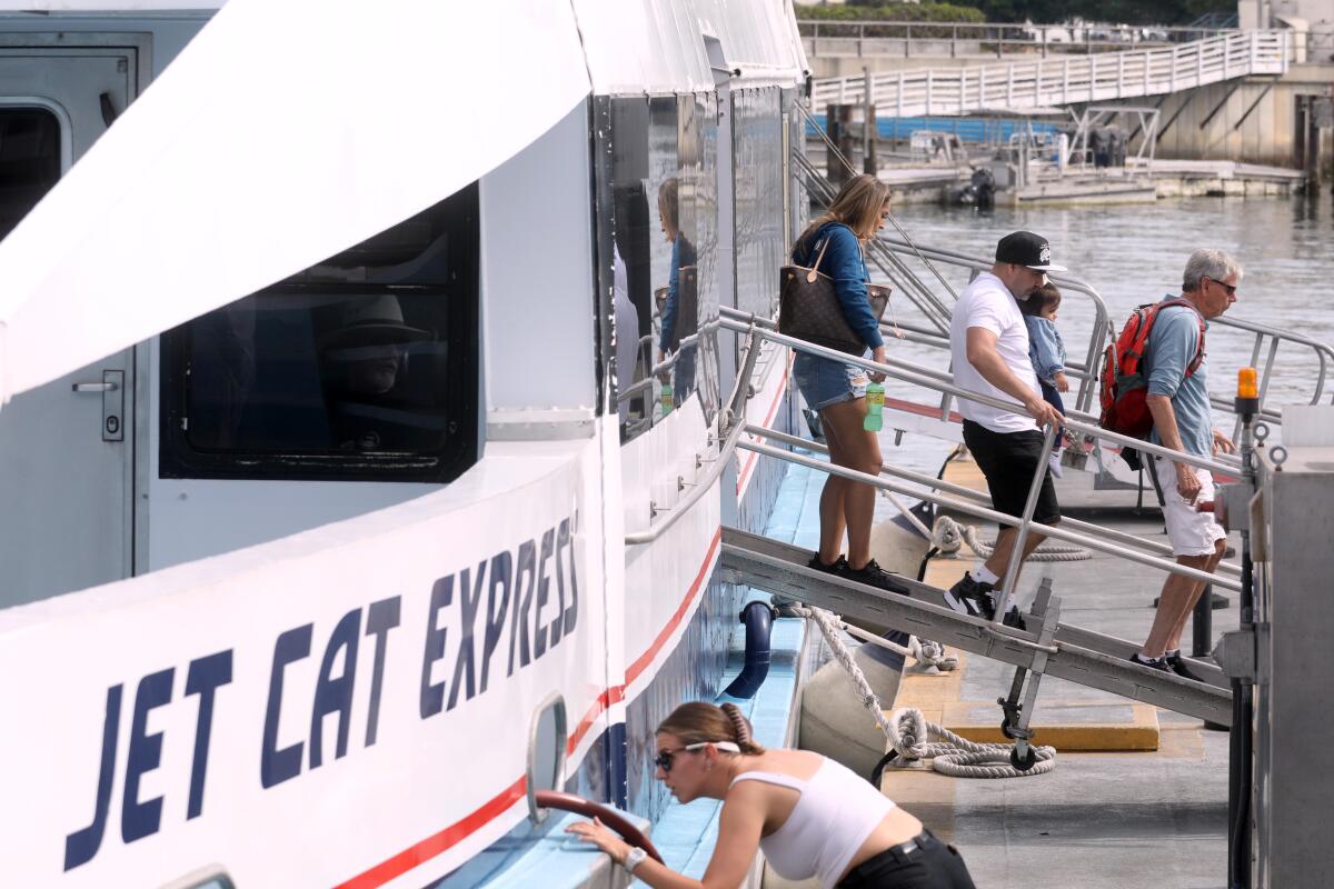 People on a ramp deboard a white and blue boat