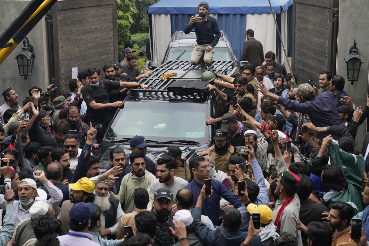 Un vehículo con el exprimer ministro Imran Khan a bordo, rodeado por los partidarios del político, abandona la casa del mandatario en Lahore, Pakistán, el 18 de marzo de 2023. (AP Foto/K.M. Chaudary)