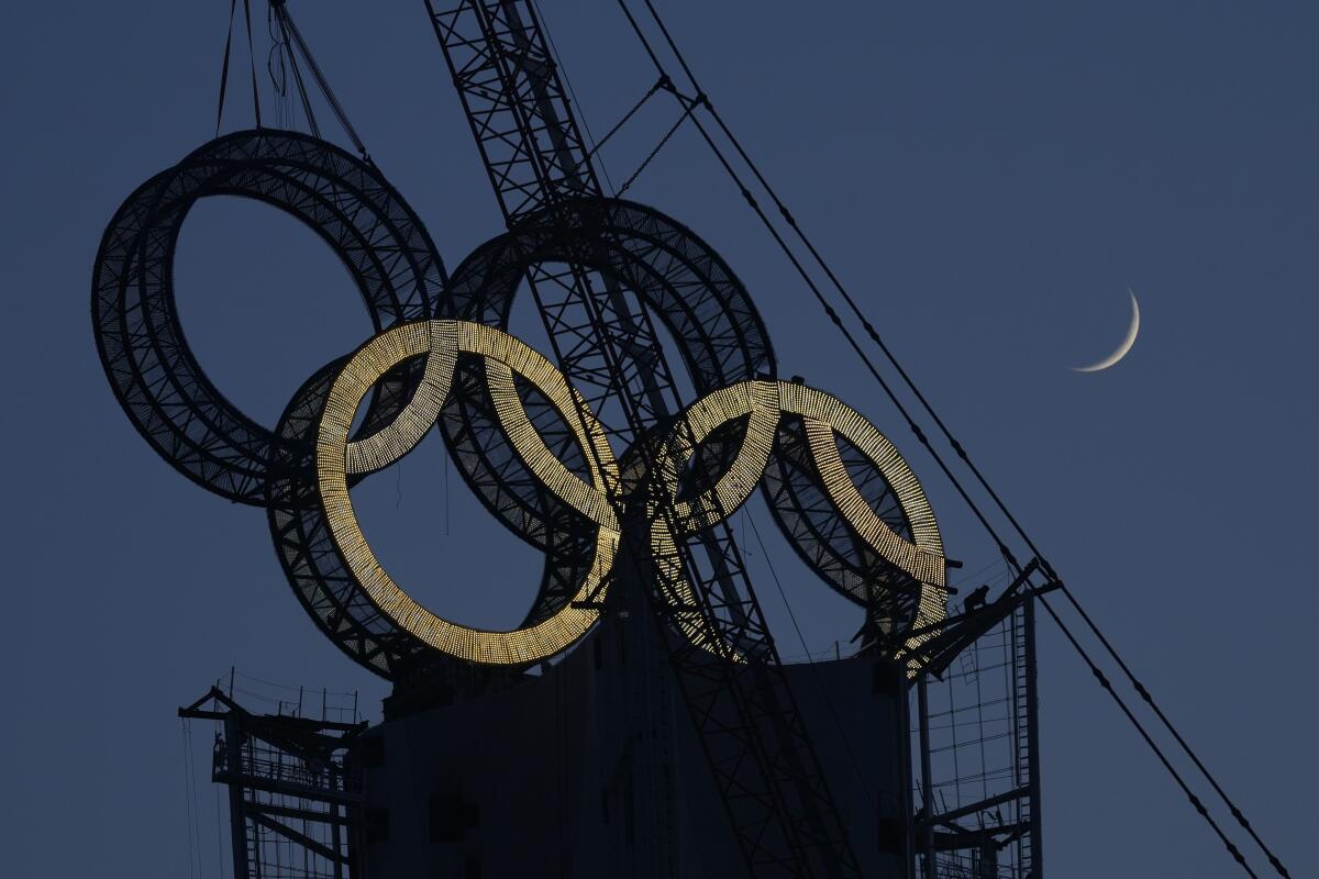 Un trabajador coloca los aros olímpicos en una torre a las afueras de Beijing,
