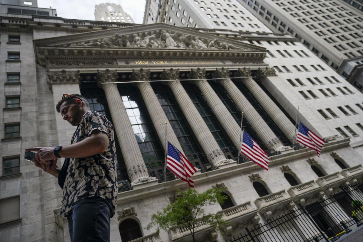 A pedestrian checks his phone outside the New York Stock Exchange. 