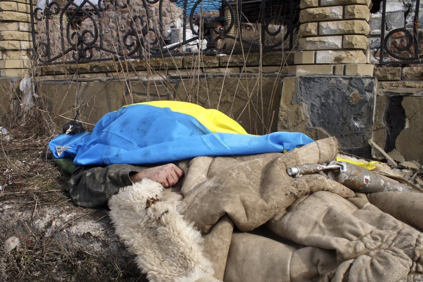 The body of a Ukrainian government soldier, covered with the national flag, lies by the side of the road Thursday in Debaltseve, the strategic rail junction taken by pro-Russia rebels two days earlier.