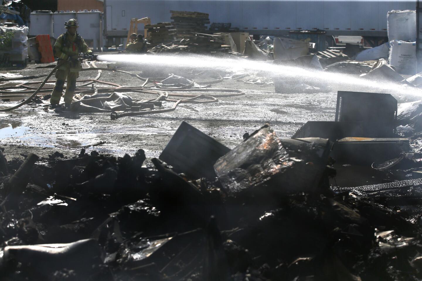 Firefighters take aim at a stubborn fire that spread from a recycling yard in Montclair to a nearby neighborhood, damaging several homes.