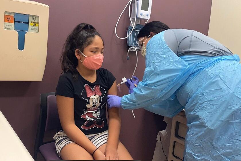 Luci Guardino, 11, receives her first dose of a COVID-19 vaccine as part of a recently launched trial at Kaiser Permanente sites in Sacramento, Oakland and Santa Clara.