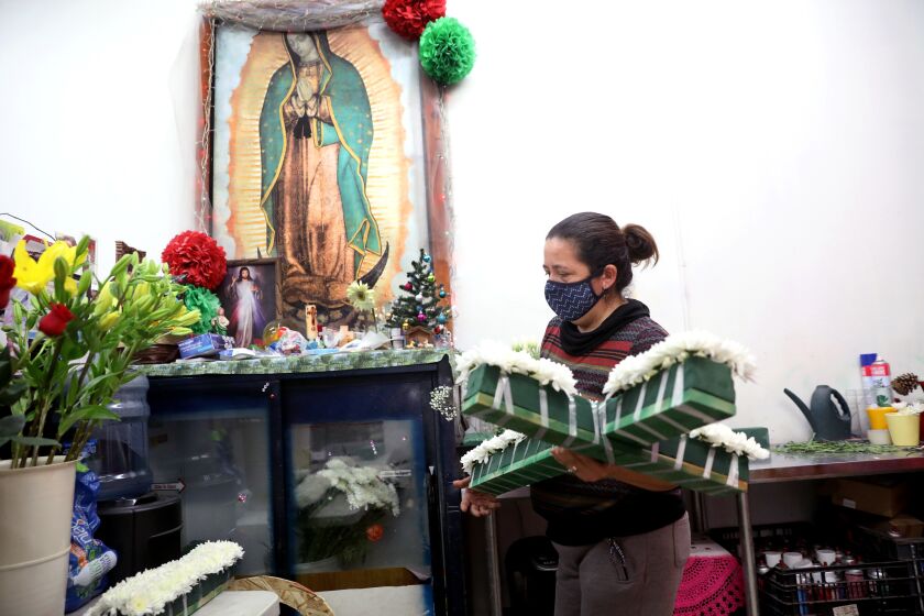 LOS ANGELES, CA - DECEMBER 17: Elizabeth Garibay, 43, prepares a floral cross for a funeral at her family business J & I Florist on Thursday, Dec. 17, 2020 in Los Angeles, CA. With business down more than 50%, Elizabeth Garibay, 43, spends most of every day hoping customers will walk into the shop while her three children attend online classes in the back. Her husband was arrested and deported during a check-in with Immigration and Customs Enforcement last December. Elizabeth now runs the business by herself while taking care of her three children. (Gary Coronado / Los Angeles Times)