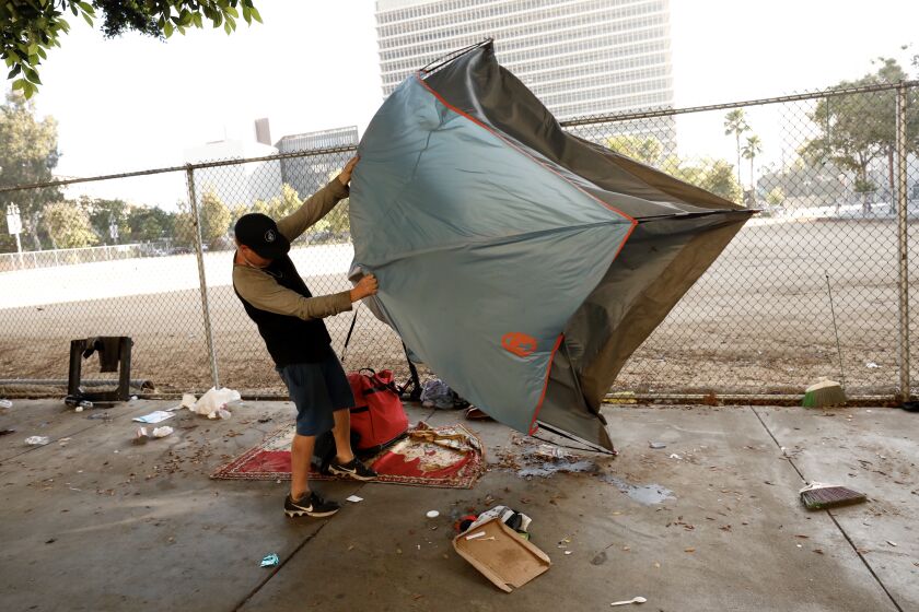 LOS ANGELES CA JULY 1, 2019 -- Homeless people pack up their belongings along First Street between Broadway and Spring Street during a cleanup Monday morning, July 1, 2019. The area targeted on First Street is the sidewalk in front of a fenced-in empty lot next to a portion of Grand Park used for parking during scheduled events. (Al Seib / Los Angeles Times)