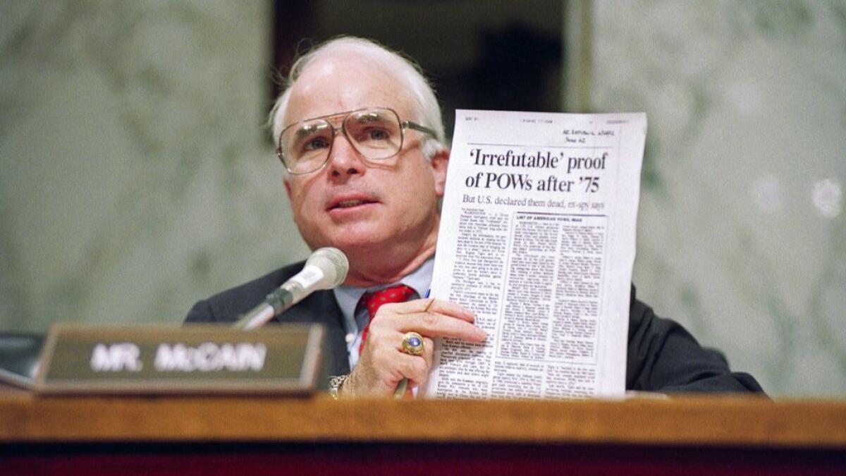 Sen. John McCain (R-Ariz.) holds up an article from the Washington Times during a hearing of the Senate Select Committee on POW/MIA Affairs on Capitol Hill in Washington in June 1992.