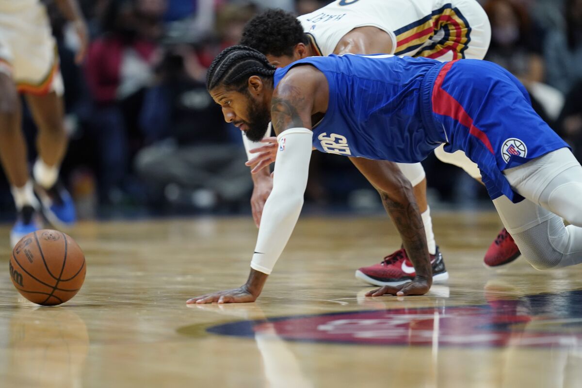 Clippers guard Paul George and New Orleans Pelicans guard Josh Hart chase down a loose ball.