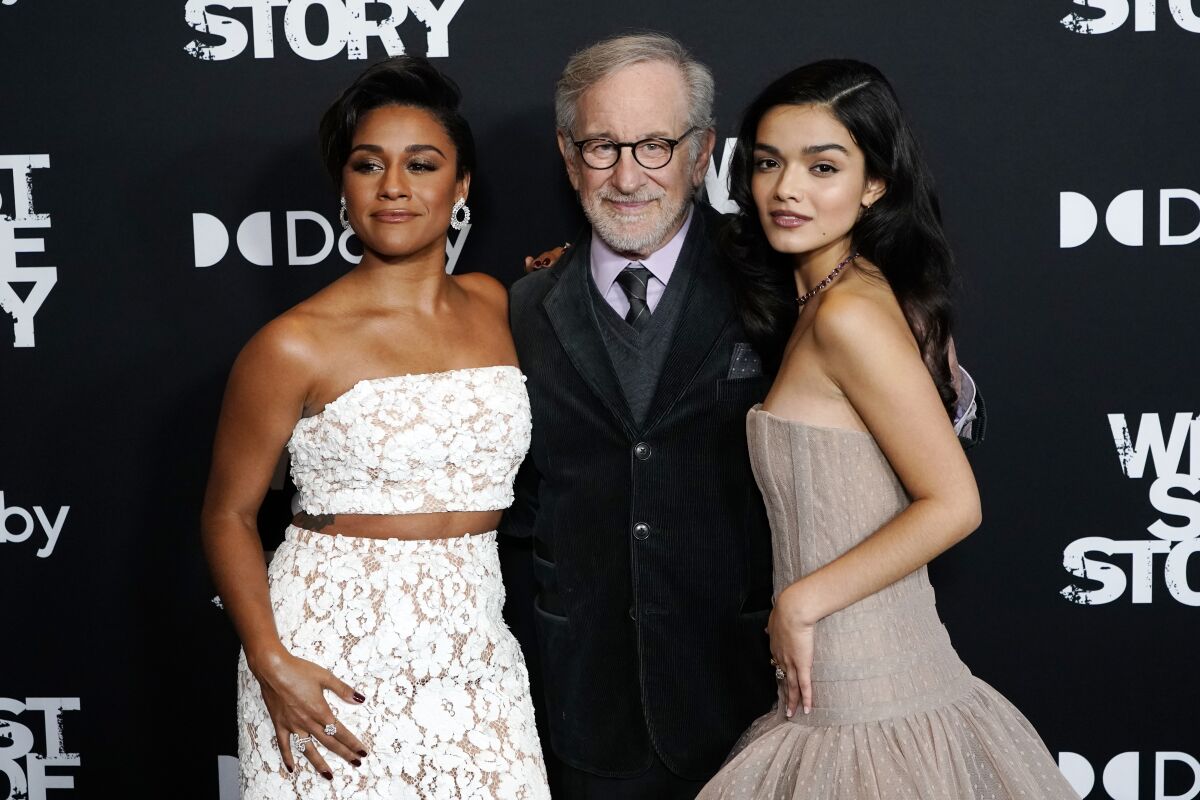 Two young women flank an older man.