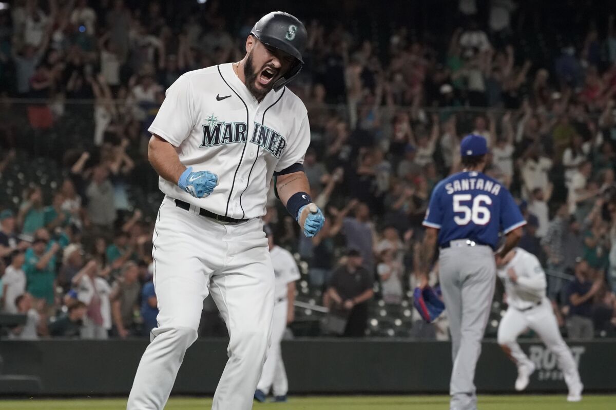 Seattle Mariners' Luis Torrens, left, celebrates his single that scored Jarred Kelenic with the winning run off of Texas Rangers pitcher Dennis Santana (56) during the ninth inning of a baseball game Wednesday, Aug. 11, 2021, in Seattle. The Mariners won 2-1. (AP Photo/Ted S. Warren)