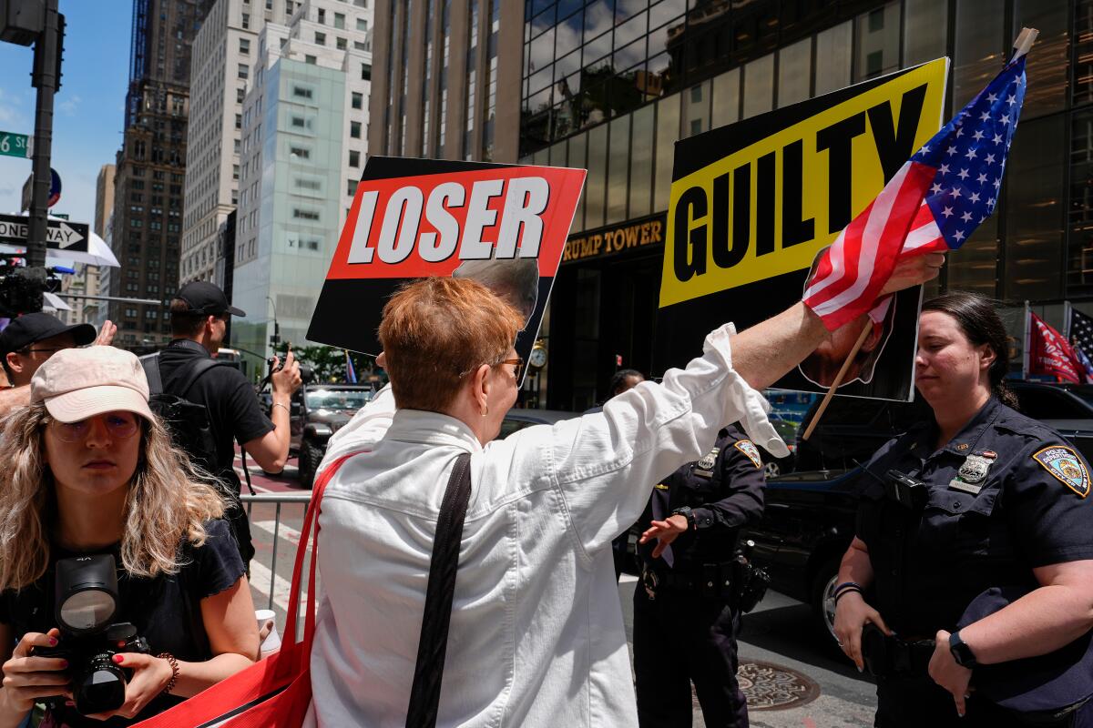 Person holds signs that read "loser" and "guilty" near police in New York