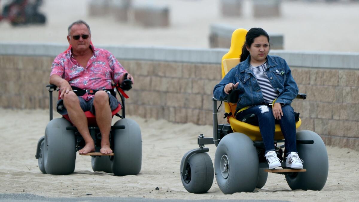 Bill Adamson of Glendora created a motorized wheelchair for his 15-year-old granddaughter, Maelisa Plumlee, for her 10th birthday. The two are seen here cruising near the Huntington Beach Pier.
