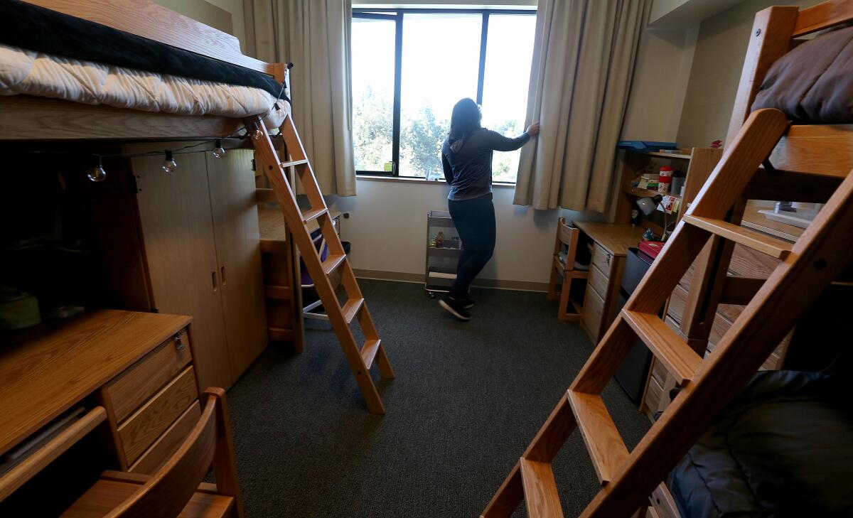 A person looks out the window of a room with several bunk beds.