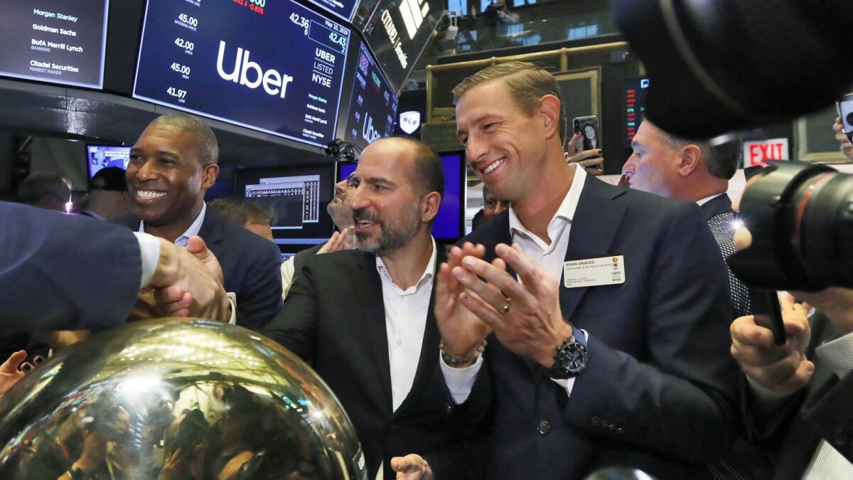 Uber CEO Dara Khosrowshahi, center, flanked by company legal officer Tony West, left, and board member Ryan Graves, on the floor of the New York Stock Exchange after the company's shares started trading Friday.