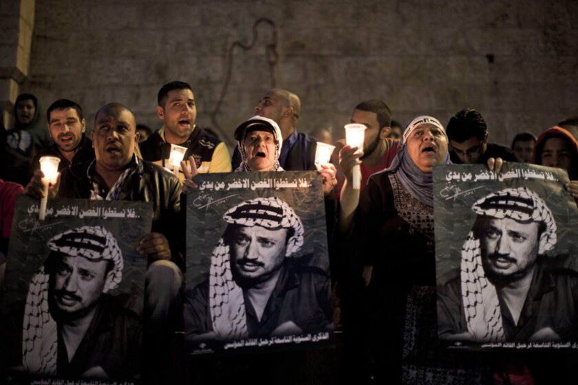Palestinians hold posters and lighted candles Monday as they commemorate the death of the late Palestinian leader Yasser Arafat at the Damascus Gate in Jerusalem's Old City.
