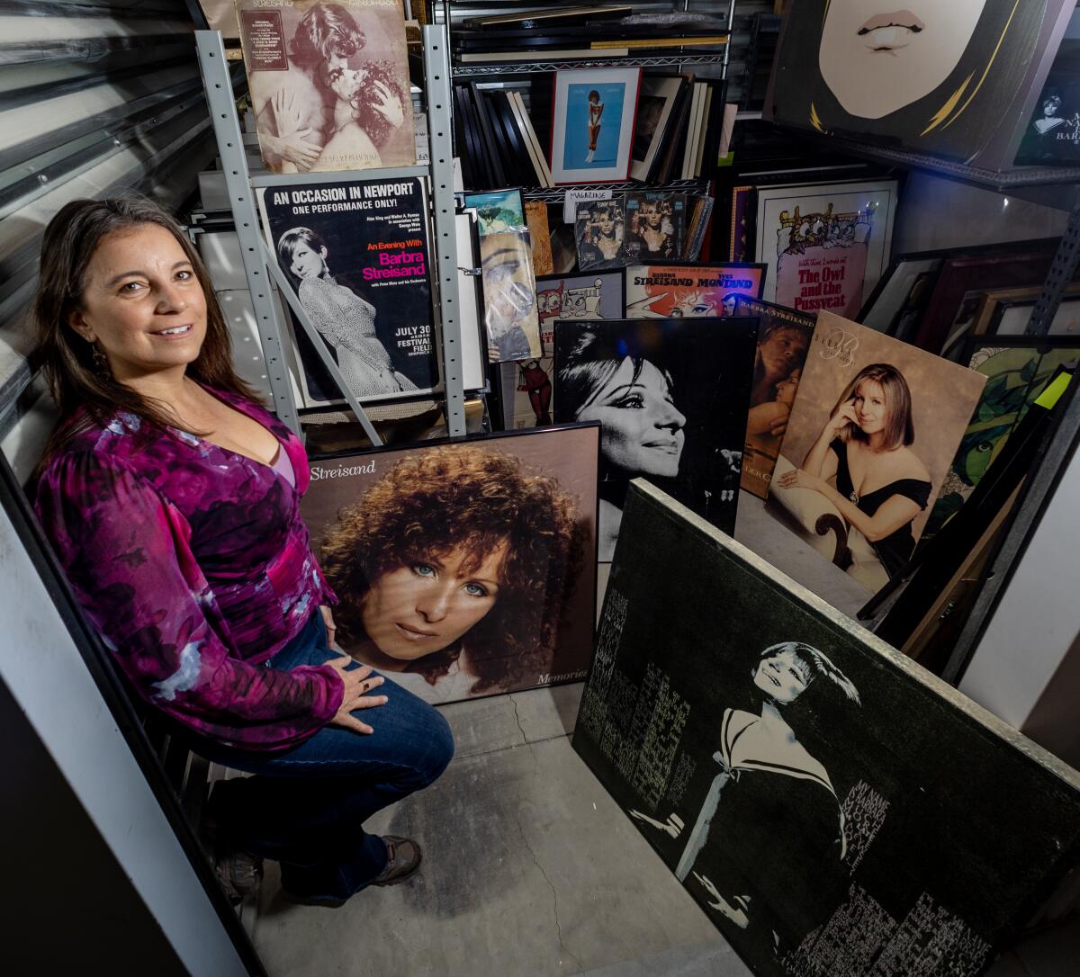 Mara Papalas stands amidst Barbra Streisand pictures and albums in a storage container.