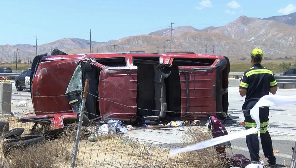 A man looks at a red Chevrolet Suburban on its side after it crashed with a Tesla on the 10 Freeway.