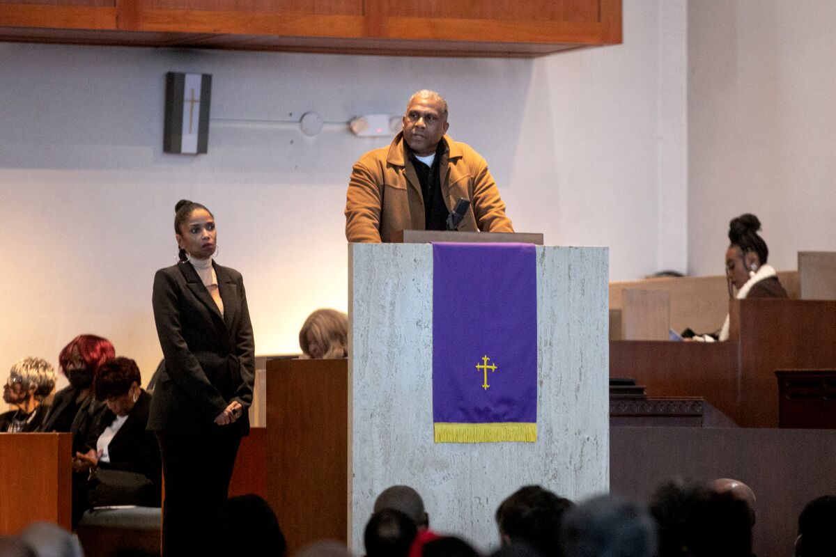 Radio talk show hosts Tavis Smiley and Areva Martin stand at a church lectern.