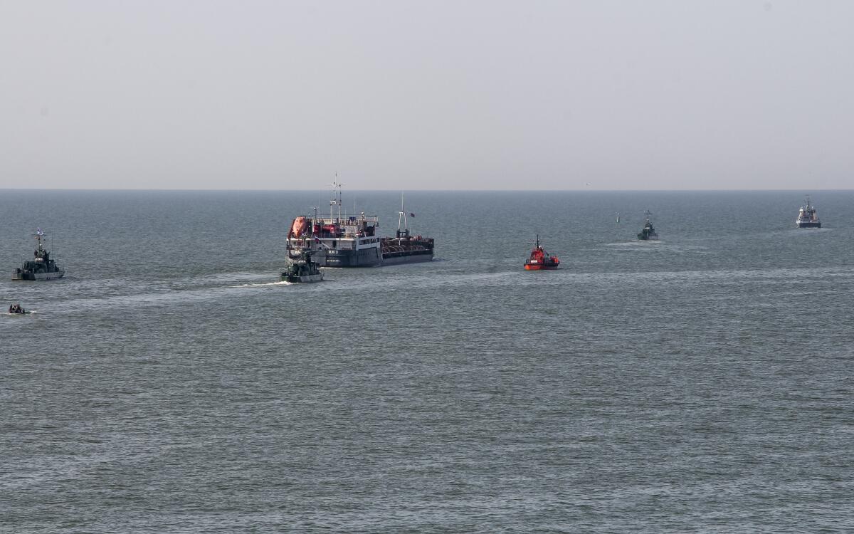 Un barco ruso, al centro, escoltado por botes militares rusos, sale del puerto de Mariúpol
