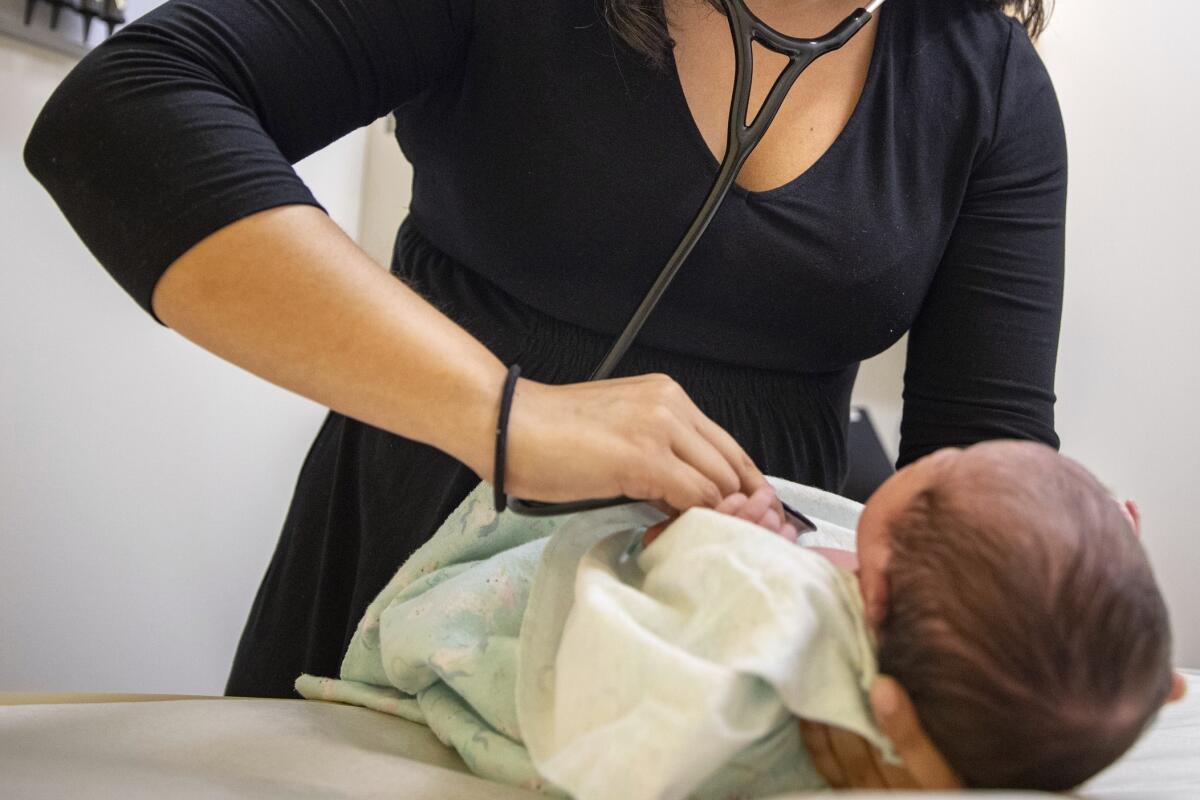 A pediatrician examines a newborn baby.
