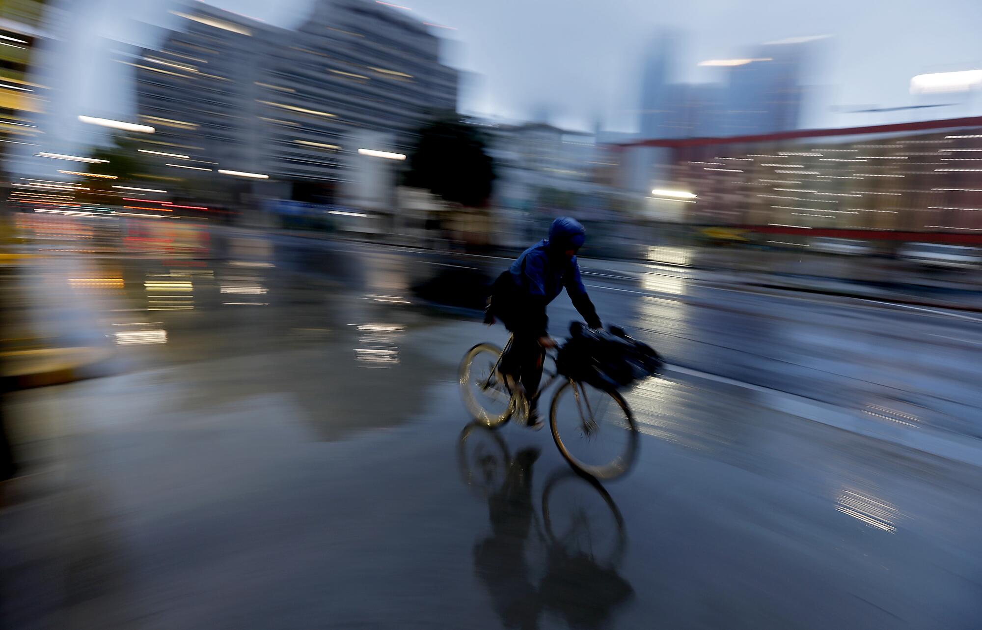 A man delivers food on a bicycle on rain-slicked Main Street in downtown Los Angeles. 