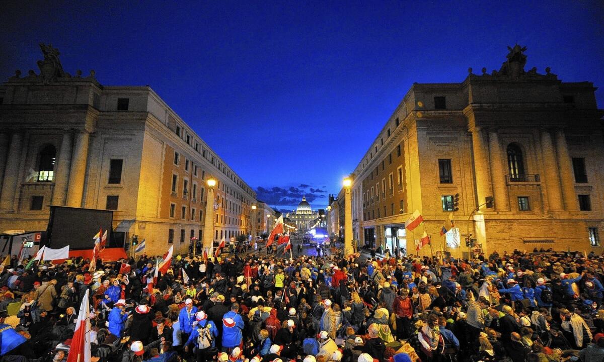 People are gathered on the Via della Conciliazione, which leads to St. Peter's Square on the eve of the canonization of Pope John Paul II and Pope John XXIII.