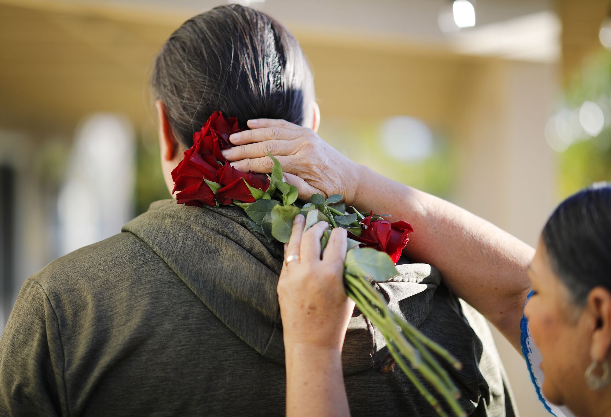 Sesma holds red roses against the back of a client's neck