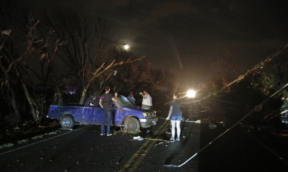 Downed trees and power lines litter the area as neighbors check a damaged pickup after reports of a tornado in Rowlett, Texas.